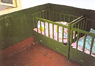 A photo of two green baby cribs... and one has a baby in it.